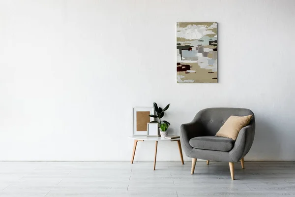 現代的なリビングルームに緑の植物やフレームとコーヒーテーブルの近くの快適なアームチェア — ストック写真
