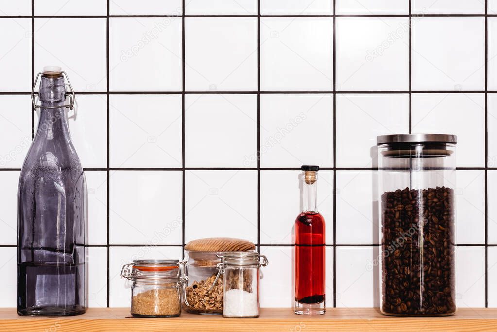 jars with granola, rice, sea salt and coffee near bottles on shelf