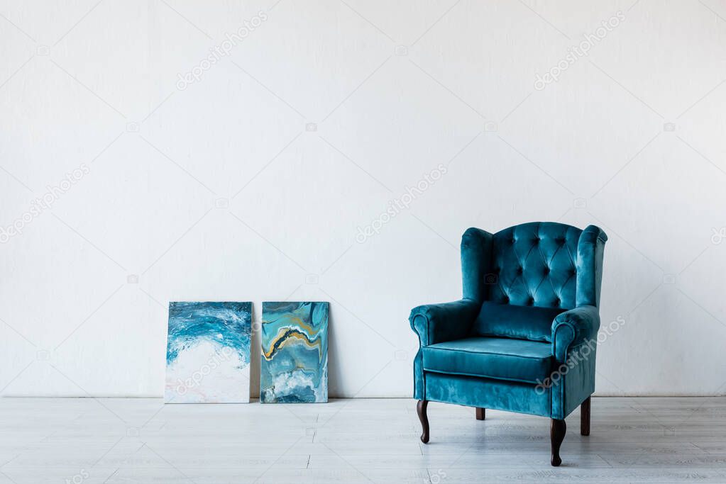 comfortable armchair near paintings in living room 