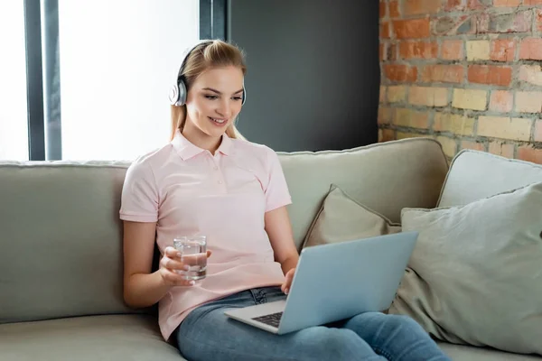 Happy Freelancer Wireless Headphones Looking Laptop Holding Glass Water Living — Stock Photo, Image
