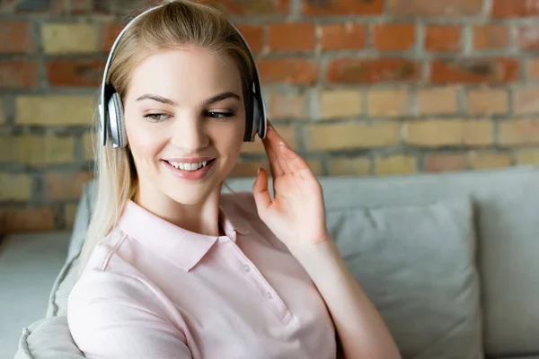 Smiling Woman Touching Wireless Headphones Home — Stock Photo, Image