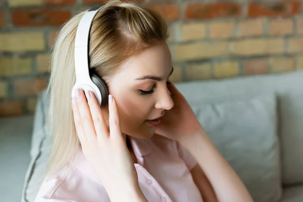 Young Woman Touching Wireless Headphones Home — Stock Photo, Image