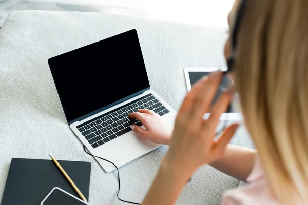 Yatağında boş ekran olan cihazların yanındaki kulaklıklara dokunan serbest çalışanın seçici odağı 