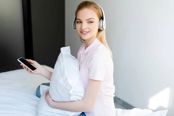 Mujer Sonriente Auriculares Inalámbricos Sosteniendo Teléfono Inteligente Con Pantalla Blanco — Foto de Stock