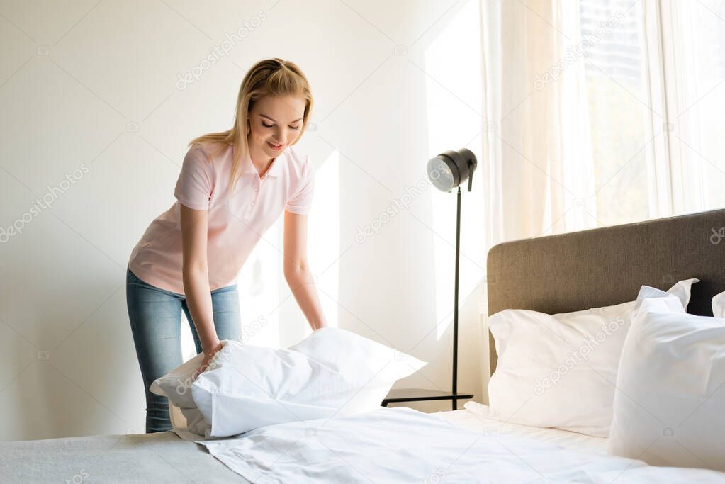 happy woman touching pillow in bedroom 