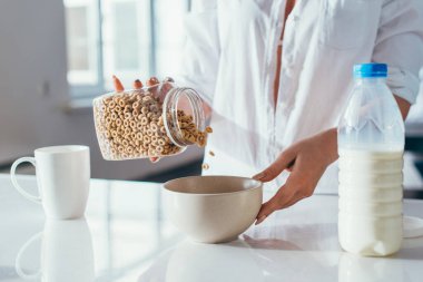 Karantinada kahvaltıda sütlü mısır gevreği yiyen bir kızın görüntüsü. 