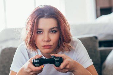 KYIV, UKRAINE - Nisan 15, 2020: kendini izole etme üzerine evde joystick ile video oyunu oynayan konsantre kız