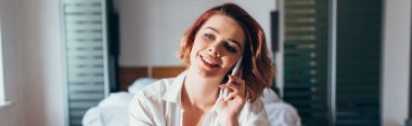 Yatak odasında kendini izole ederken akıllı telefondan konuşan mutlu bir kız. 