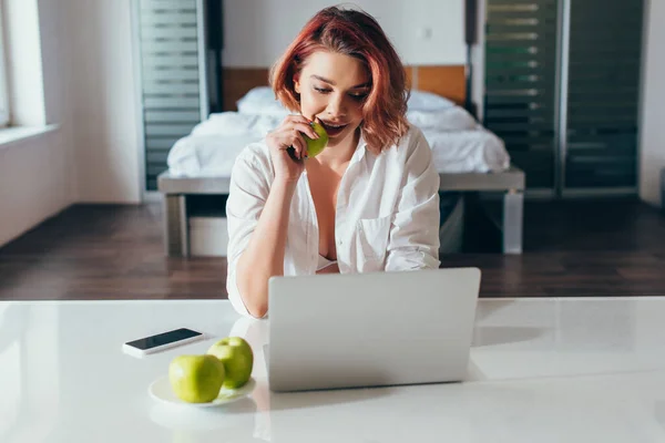 Feliz Chica Hablando Comer Manzana Mientras Utiliza Ordenador Portátil Casa — Foto de Stock