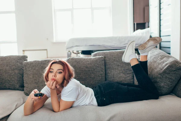 自宅でテレビを見ているリモコンを持つ退屈な女性 — ストック写真