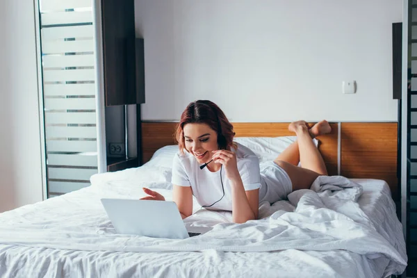Усміхнена Дівчина Робить Відеодзвінок Гарнітурою Ноутбуком Ліжку Під Час Самоізоляції — стокове фото