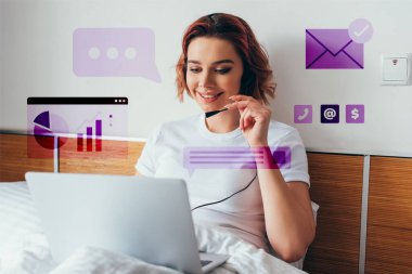 smiling freelancer making video call with headset and laptop in bed during quarantine with business signs clipart