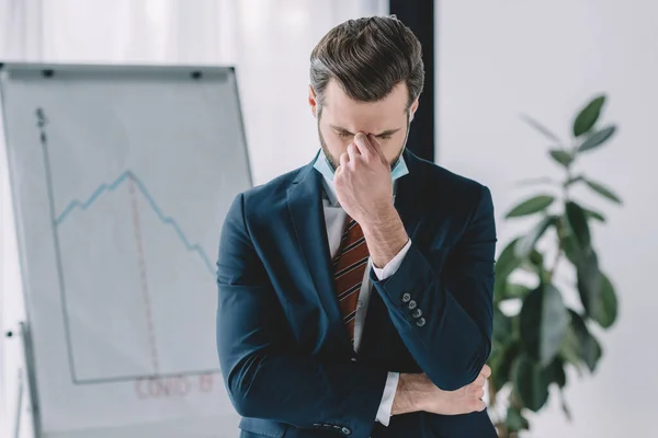 Homme d'affaires déprimé debout avec la tête inclinée et les yeux fermés près de paperboard avec des graphiques montrant la récession — Photo de stock