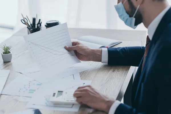 Vue recadrée de l'homme d'affaires en masque médical travaillant avec des documents sur le lieu de travail — Photo de stock