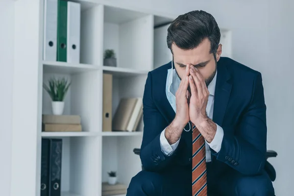 Uomo d'affari depresso toccare il viso mentre seduto in ufficio con la testa piegata e gli occhi chiusi — Foto stock
