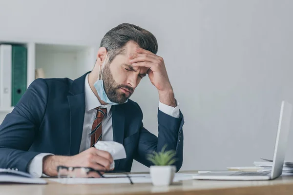 Selectivo centrado en agotado, molesto empresario sosteniendo papel arrugado mientras que sufre de dolor de cabeza con los ojos cerrados - foto de stock