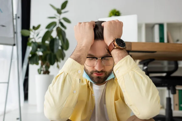Deprime hombre de negocios cogido de la mano en la cabeza mientras está sentado en la oficina con los ojos cerrados - foto de stock