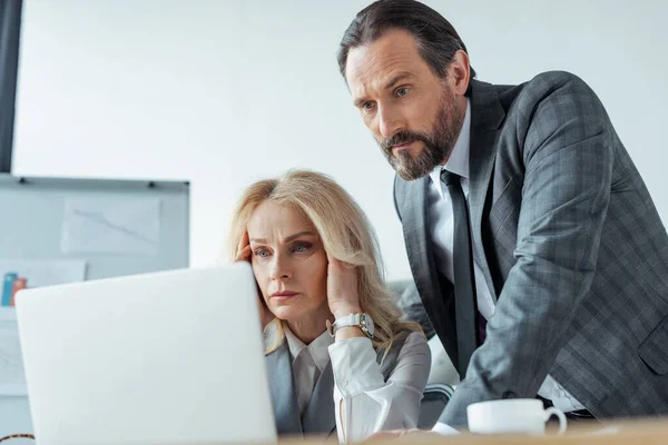 Вибірковий фокус концентрованих бізнесменів, які дивляться на ноутбук в офісі — стокове фото