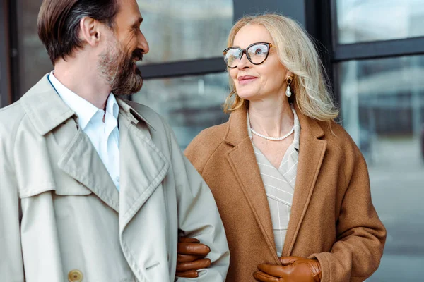 Lächelnde Geschäftsfrau schaut gutaussehenden Geschäftsmann in der Nähe eines Gebäudes an der Stadtstraße an — Stockfoto