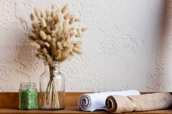 Chatons en fleurs, rouleaux de serviettes et sel de mer vert dans un bocal sur une étagère en bois — Photo de stock