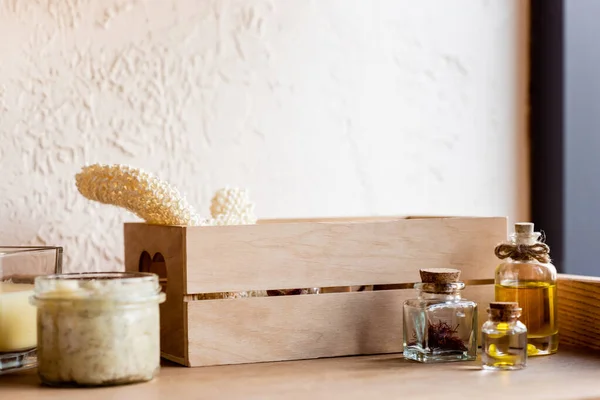 Caja de madera, con esponja, botellas de aceite, máscara de arcilla en frasco y vela en estante - foto de stock