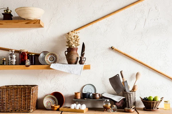 Mugs and bowls near knifes raw eggs, herbs and tasty fruits in kitchen — Stock Photo