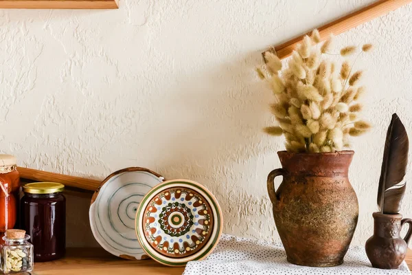 Amentos esponjosos en jarra de arcilla cerca de cuencos y frascos en la cocina - foto de stock