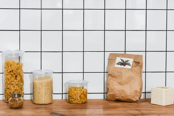 Jars with dried pasta and rice near paper bag — Stock Photo