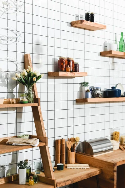 Grüne Pflanzen, Blumen, Gläser mit Tomatenkonserven, Bambusdämpfer und Kochutensilien in den Regalen — Stockfoto