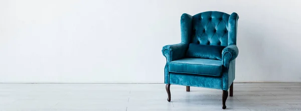 Panoramic crop of blue and comfortable armchair near white wall in living room — Stock Photo