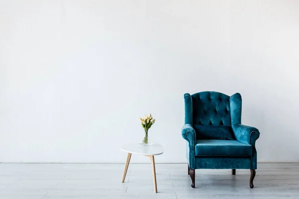 Comfortable armchair near tulips on coffee table in living room — Stock Photo