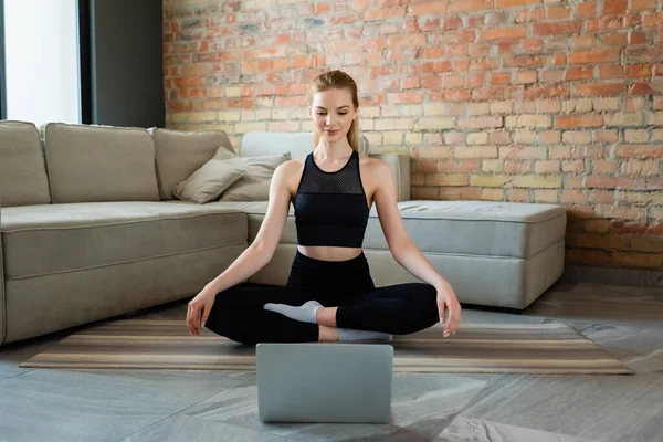 Happy sportswoman socks and yoga pose watching online yoga exercise on laptop — Stock Photo