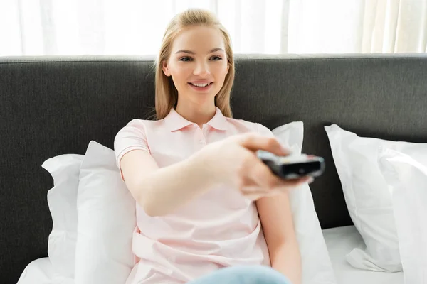 Selective focus of girl holding remote controller and watching movie at home — Stock Photo