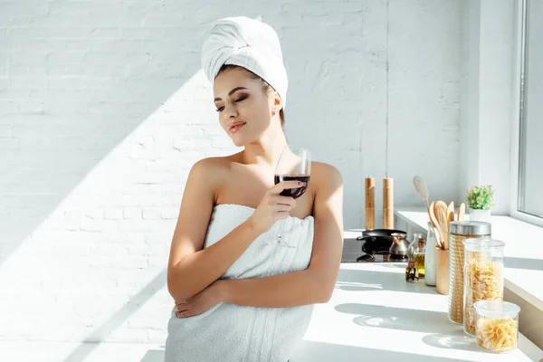 Mulher bonita envolto em toalhas segurando copo de vinho na cozinha — Fotografia de Stock