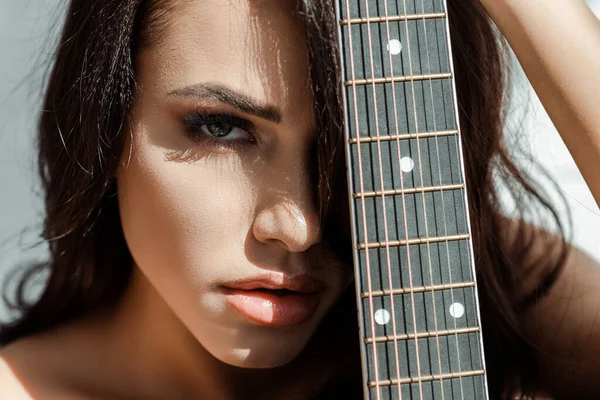 Beautiful woman looking at camera while holding acoustic guitar — Stock Photo