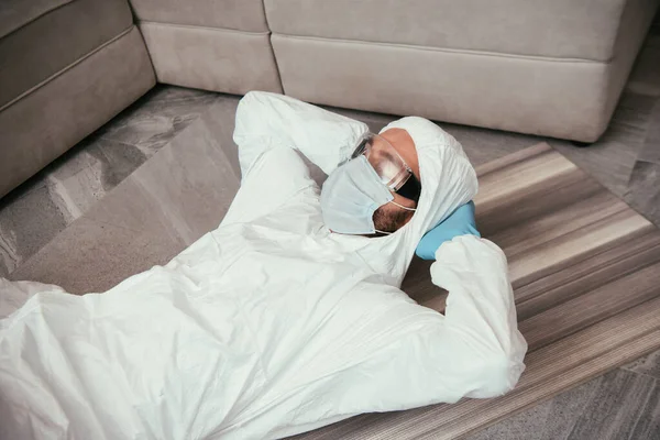 Homem em terno hazmat, máscara médica e óculos exercendo em casa — Fotografia de Stock