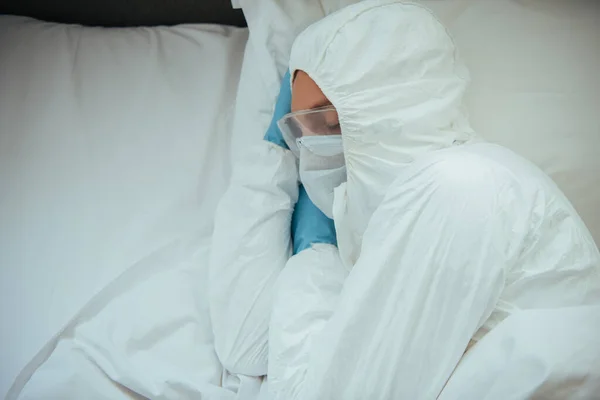 Vista superior do homem em terno hazmat, máscara médica e óculos de dormir na cama — Fotografia de Stock