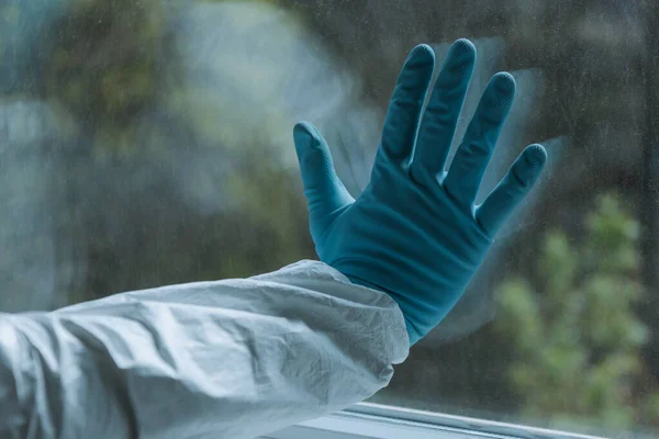 Vue recadrée de l'homme en gant de latex touchant fenêtre, concept de quarantaine — Photo de stock