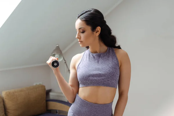 Atractiva chica atlética en entrenamiento de ropa deportiva con mancuernas en casa - foto de stock