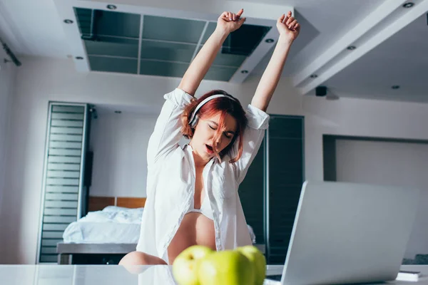 Beautiful girl listening music in headphones, dancing and singing at home with laptop on quarantine — Stock Photo