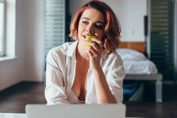 Attraktives fröhliches Mädchen, das zu Hause in Quarantäne Apfel isst — Stockfoto