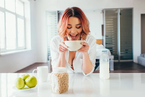 Attraente divertente ragazza leccare cornflakes con latte durante la prima colazione su auto isolamento — Foto stock