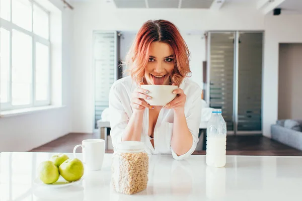 Divertente ragazza leccare cornflakes con latte per la prima colazione durante la quarantena — Foto stock