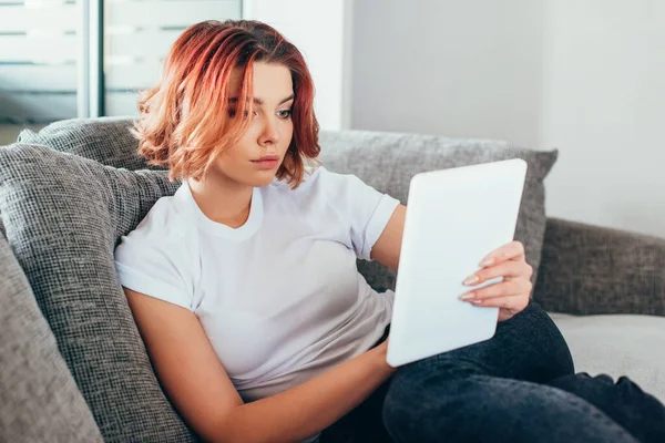 Attractive bored girl using digital tablet on sofa during quarantine — Stock Photo