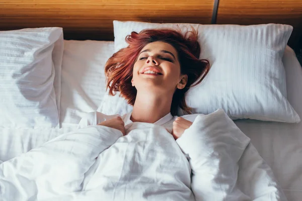 Attractive smiling girl relaxing in bed in morning during quarantine — Stock Photo
