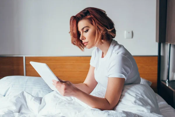 Bela jovem mulher usando tablet digital na cama em quarentena — Fotografia de Stock