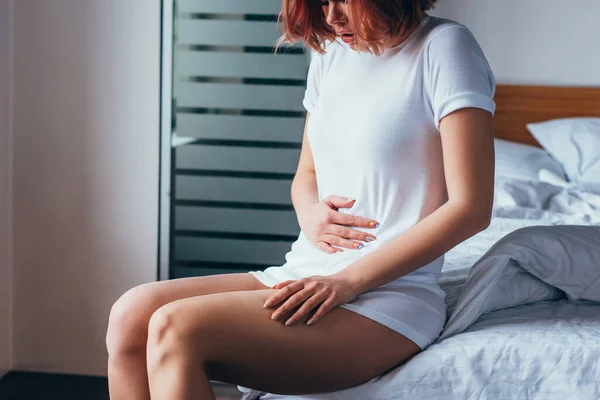 Cropped view of girl suffering from stomachache at home on self isolation — Stock Photo