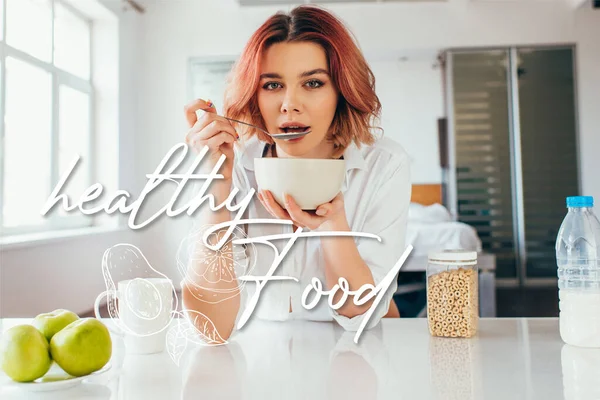 Attractive girl eating cornflakes with milk for breakfast during quarantine with healthy food lettering — Stock Photo