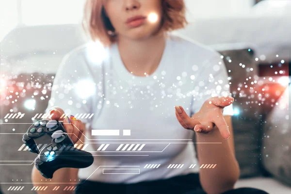 KYIV, UKRAINE - APRIL 15, 2020: cropped view of sad girl playing video game with joystick at home on self isolation with geometric signs — Stock Photo