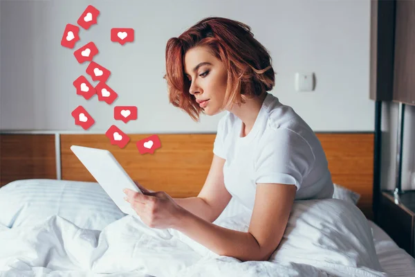 Hermosa joven usando tableta digital con signos cardíacos en la cama en cuarentena - foto de stock